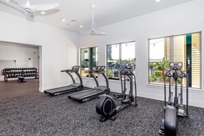Een fitnessruimte met loopbanden, elliptische trainers en een rek voor gewichten.