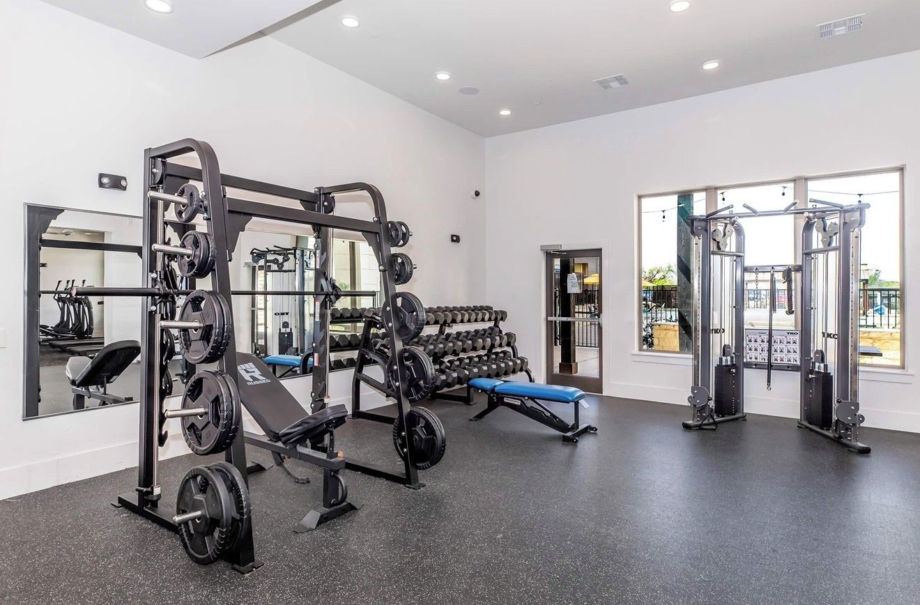 A gym with weightlifting equipment, benches, and dumbbells.