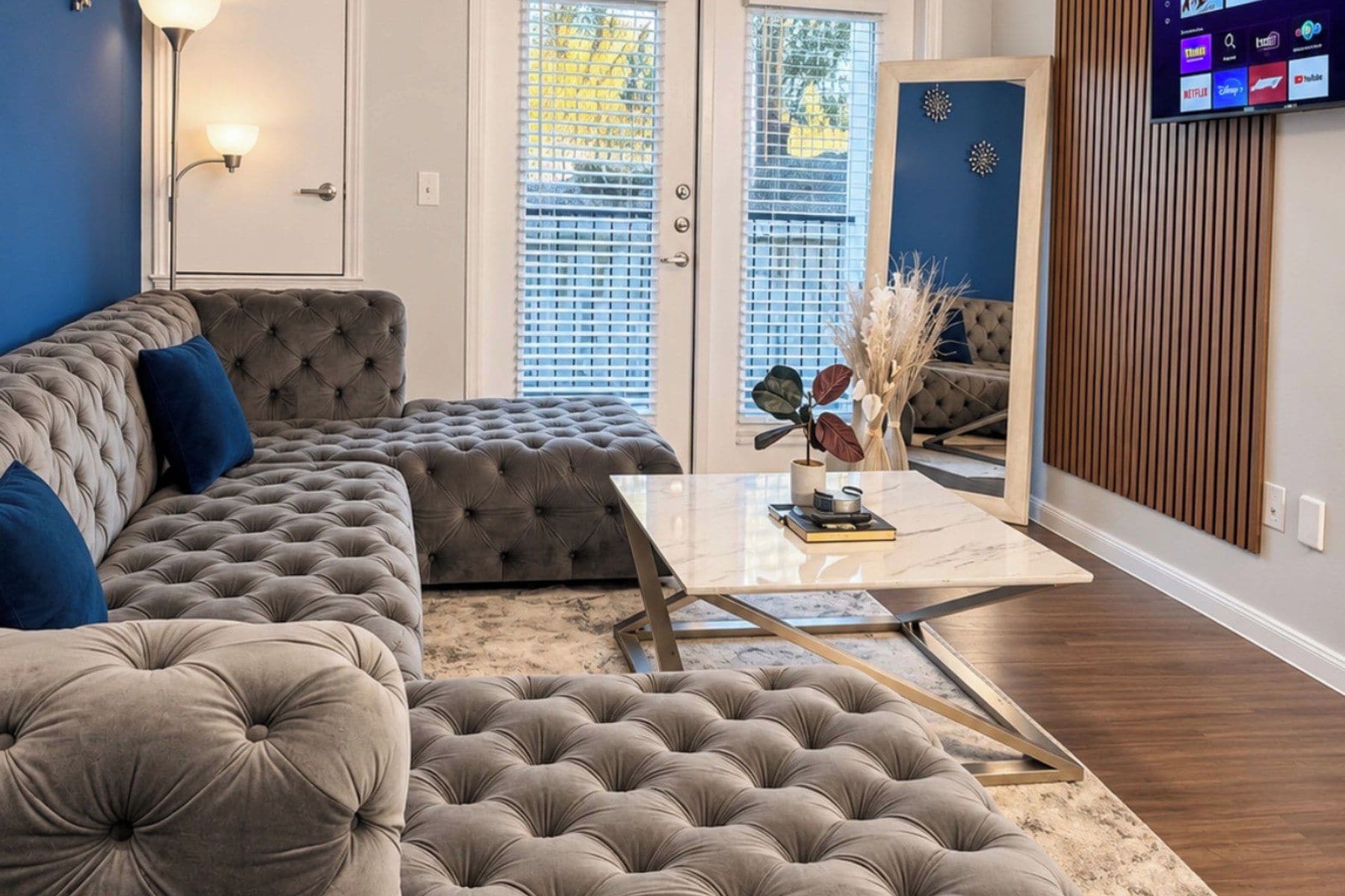 A living room with a sectional sofa, a coffee table, and a television mounted on the wall.