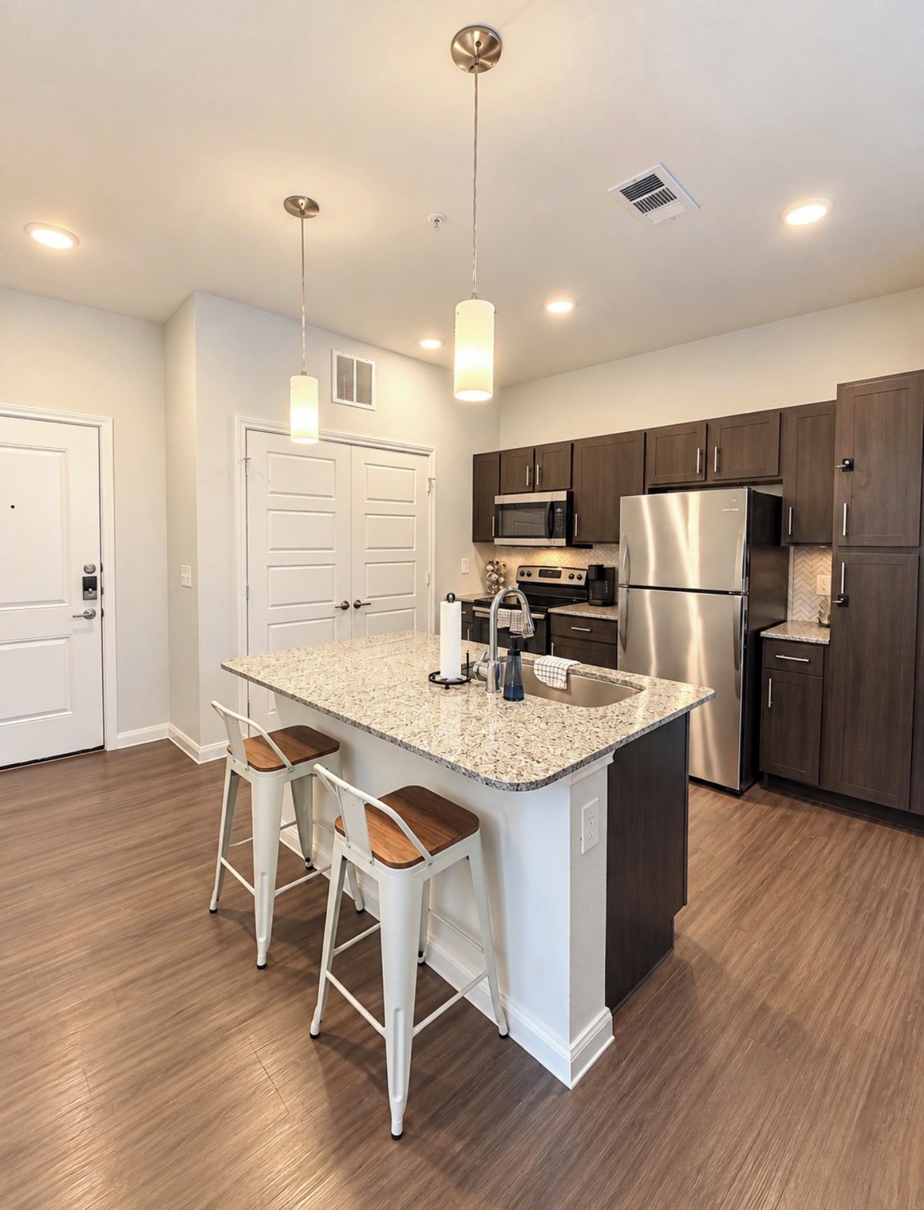 A modern kitchen with a central island, stainless steel appliances, and pendant lighting.