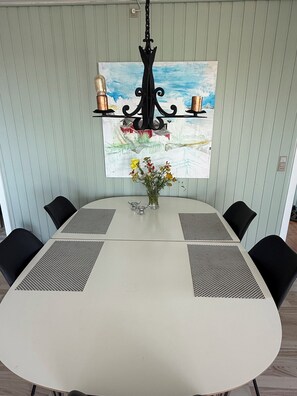 A dining area with a round table, black chairs, a vase with flowers, and a painting on the wall. - Holiday home with sea views near the beach (Egernsund)