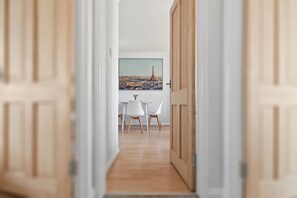 A hallway leading to a dining area with a view of a cityscape, including a prominent tower. - The Primrose Loft | Garden Views | Regents Park (Greater London)