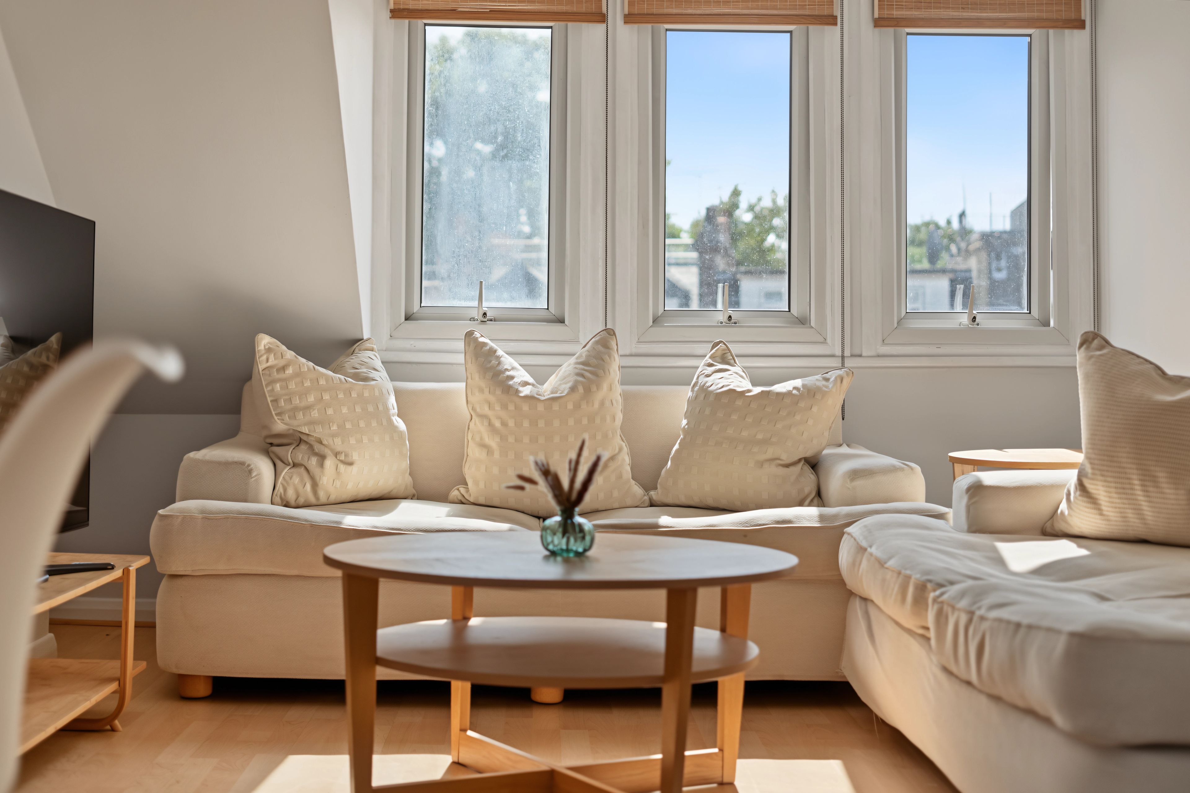 A modern living room with a sectional sofa, a round coffee table, and a TV on a stand.