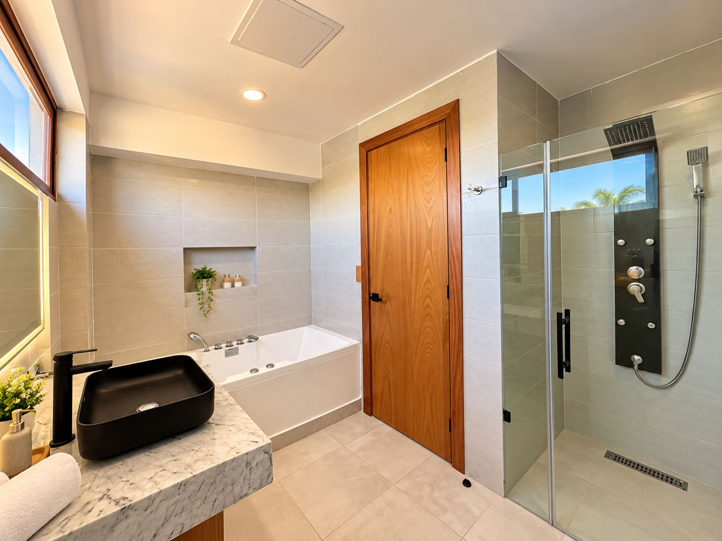 Un baño moderno con una bañera independiente, ducha con cerramiento de vidrio y puerta de madera.