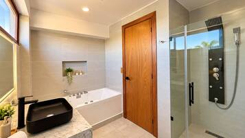 Un baño moderno con una bañera independiente, ducha con cerramiento de vidrio y puerta de madera.