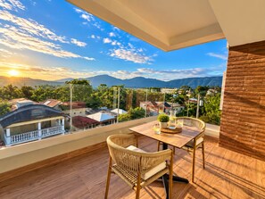 A balcony with a view of a cityscape and mountains, featuring a table and two chairs. - New Listing (Jarabacoa)