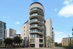 En moderne bygning med flere etager, en buet facade, store vinduer og altaner.