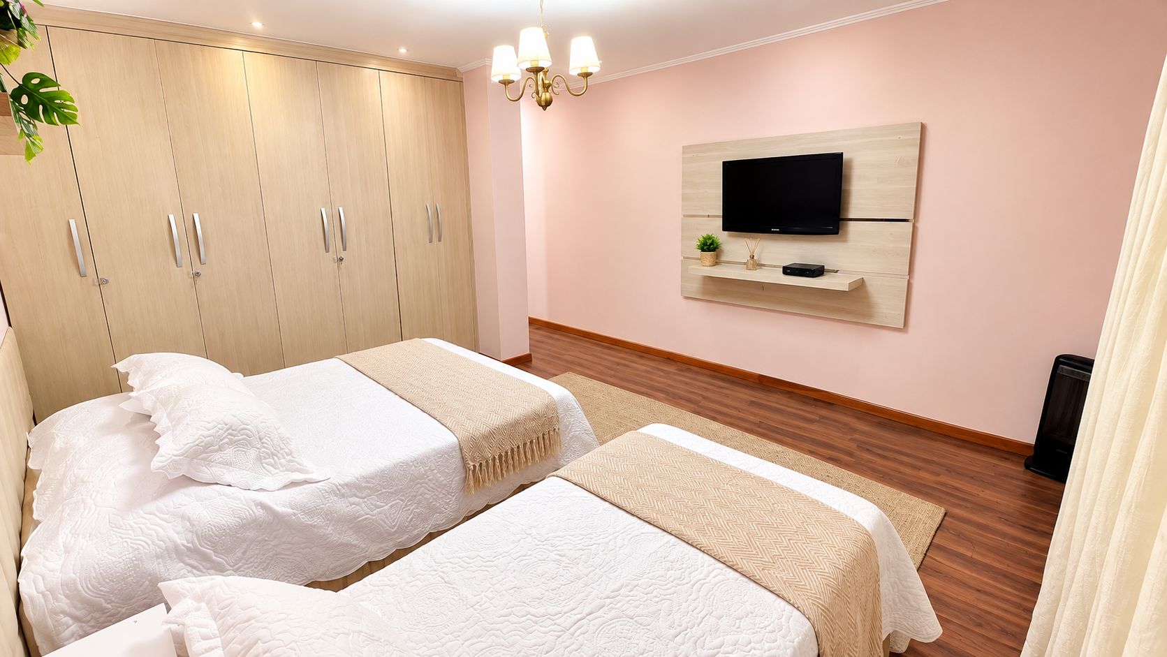 Une chambre d’hôtel avec deux lits, un téléviseur fixé au mur et une armoire.