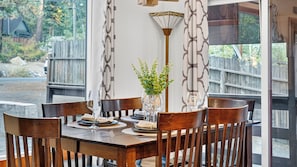 A dining table with chairs, a vase with greenery, and a patterned wall. - Emberpine by Avantstay Hot Tub + Pine-view Decks Near Speedboat Beach + Crystal Bay (Kings Beach)