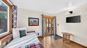 Ein Hotelzimmer mit einem Bett, einem Fernseher, einer zur Außenseite führenden Tür und einem kleinen Tisch.