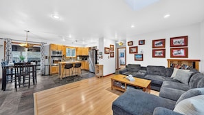 A modern living room with a grey sofa, wooden coffee table, and a dining area with a glass table and chairs. - Emberpine by Avantstay Hot Tub + Pine-view Decks Near Speedboat Beach + Crystal Bay (Kings Beach)