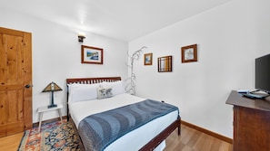 A bedroom with a bed, a desk, a television, and a wardrobe. - Emberpine by Avantstay Hot Tub + Pine-view Decks Near Speedboat Beach + Crystal Bay (Kings Beach)