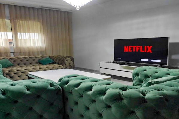 Una sala de estar con un sofá, una mesa de centro y un televisor mostrando el logotipo de Netflix.