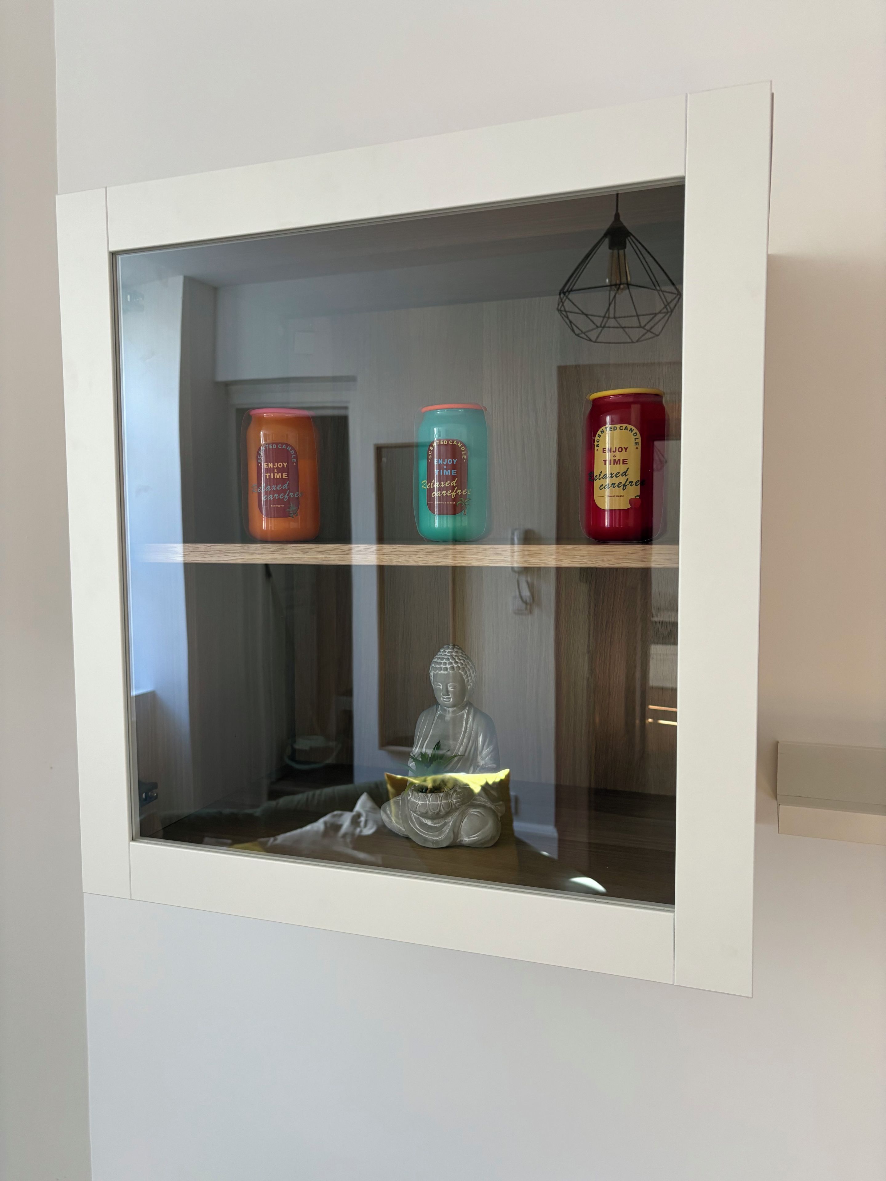 Um expositor com três velas aromáticas e uma estátua de Buda.