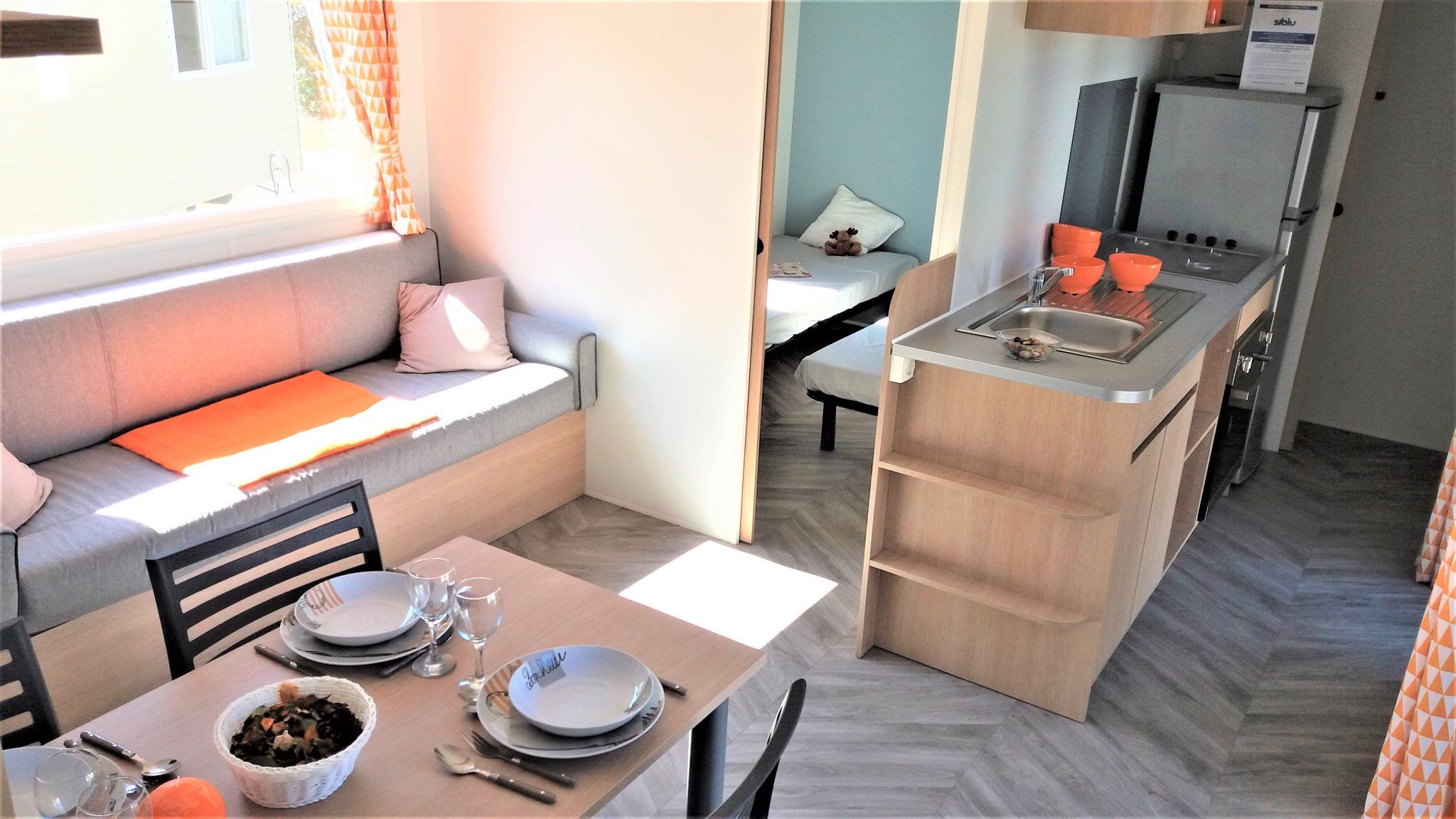 Un espacio habitable compacto con kitchenette, zona de comedor y sofá con cojines.
