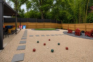 An outdoor area with a gravel surface, stepping stones, and red Adirondack chairs. - CLT Maison: 5BR Charlotte Retreat with Sauna, Hot Tub, Game Room & Gym (Charlotte)