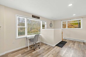 Ein Zimmer mit Schreibtisch, Stuhl und einem Fenster mit Jalousien.