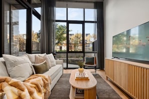 Un salon moderne avec un canapé, une table basse et un grand téléviseur à écran plat.