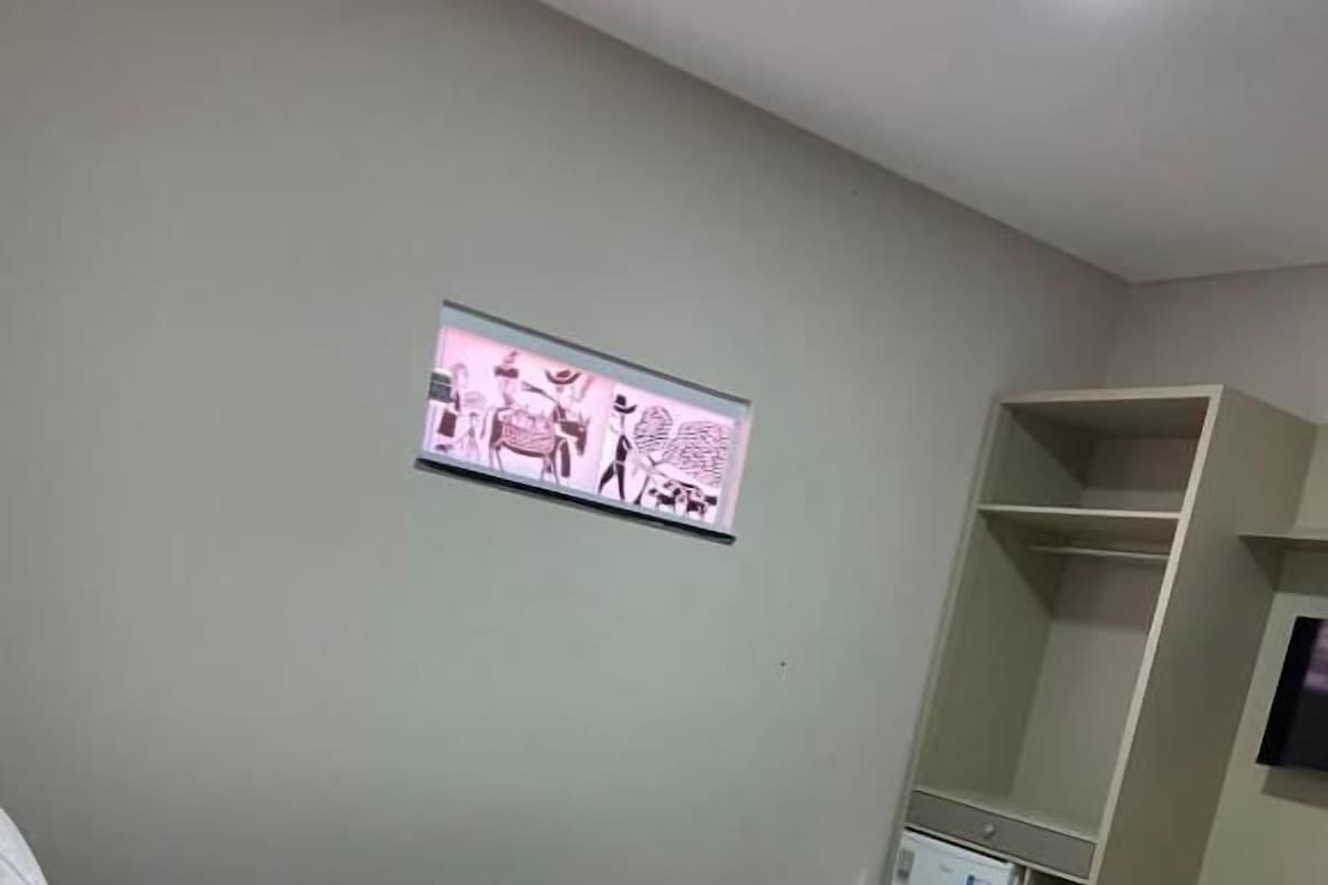 Une chambre d’hôtel équipée d’un lit, d’un téléviseur fixé au mur et d’un petit réfrigérateur.