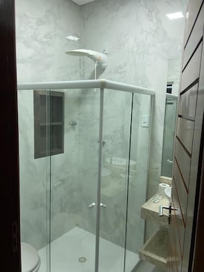 Une salle de bain moderne avec une douche à parois de verre, des toilettes et un lavabo.
