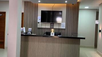 A reception desk with a flat-screen TV, a coffee machine, and a sign indicating Wi-Fi availability.