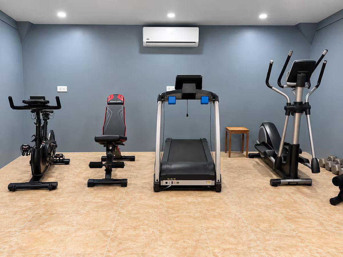 Ein Heimfitnessraum mit Laufband, Crosstrainer, Ergometer und Gewichten.