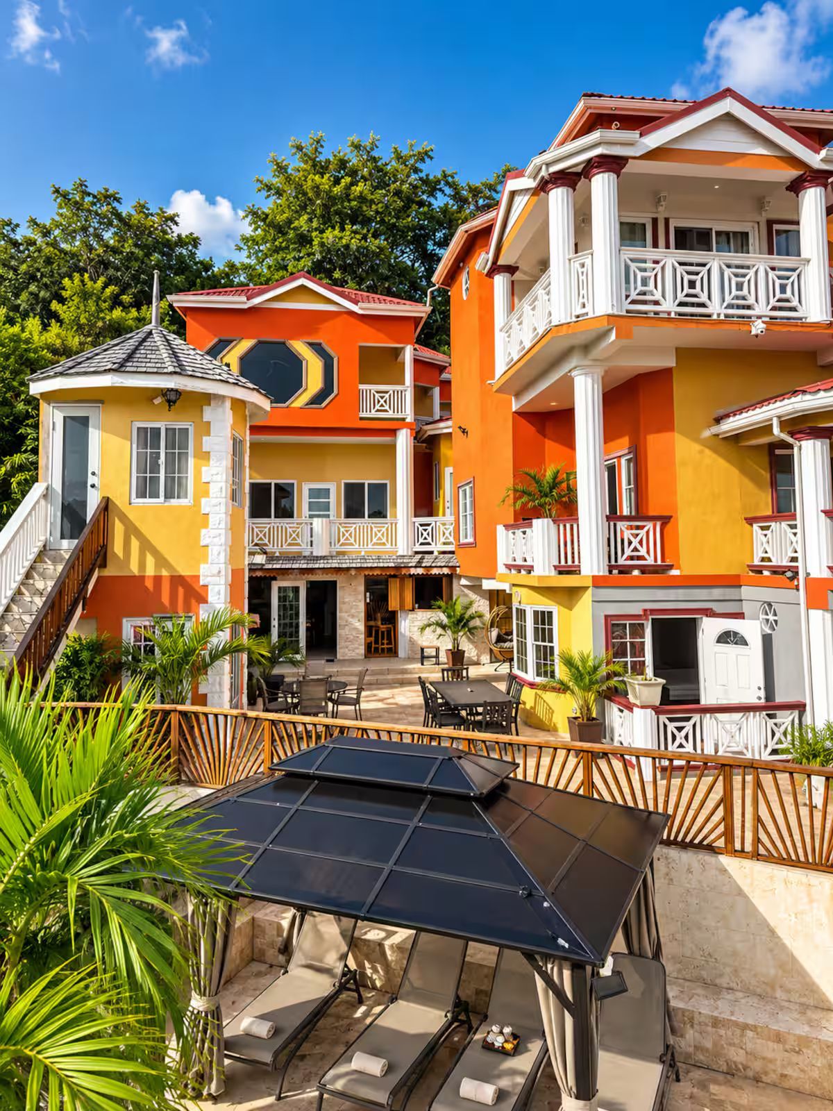 A multi-story building with balconies, outdoor seating, and a solar panel.