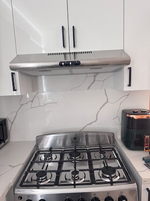 A kitchen with a stainless steel stove, white cabinets, and a marble backsplash. - Brand-New Modern Retreat in Sosúa (Sosua)