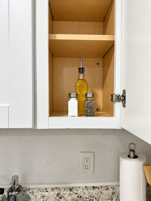 A kitchen cabinet with a wooden interior, a bottle, and two spice jars.