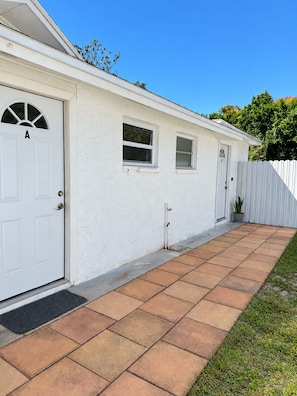 Edifici residencial amb façana blanca, entrada enrajolada, porta marcada amb una 'A' i una finestra petita.