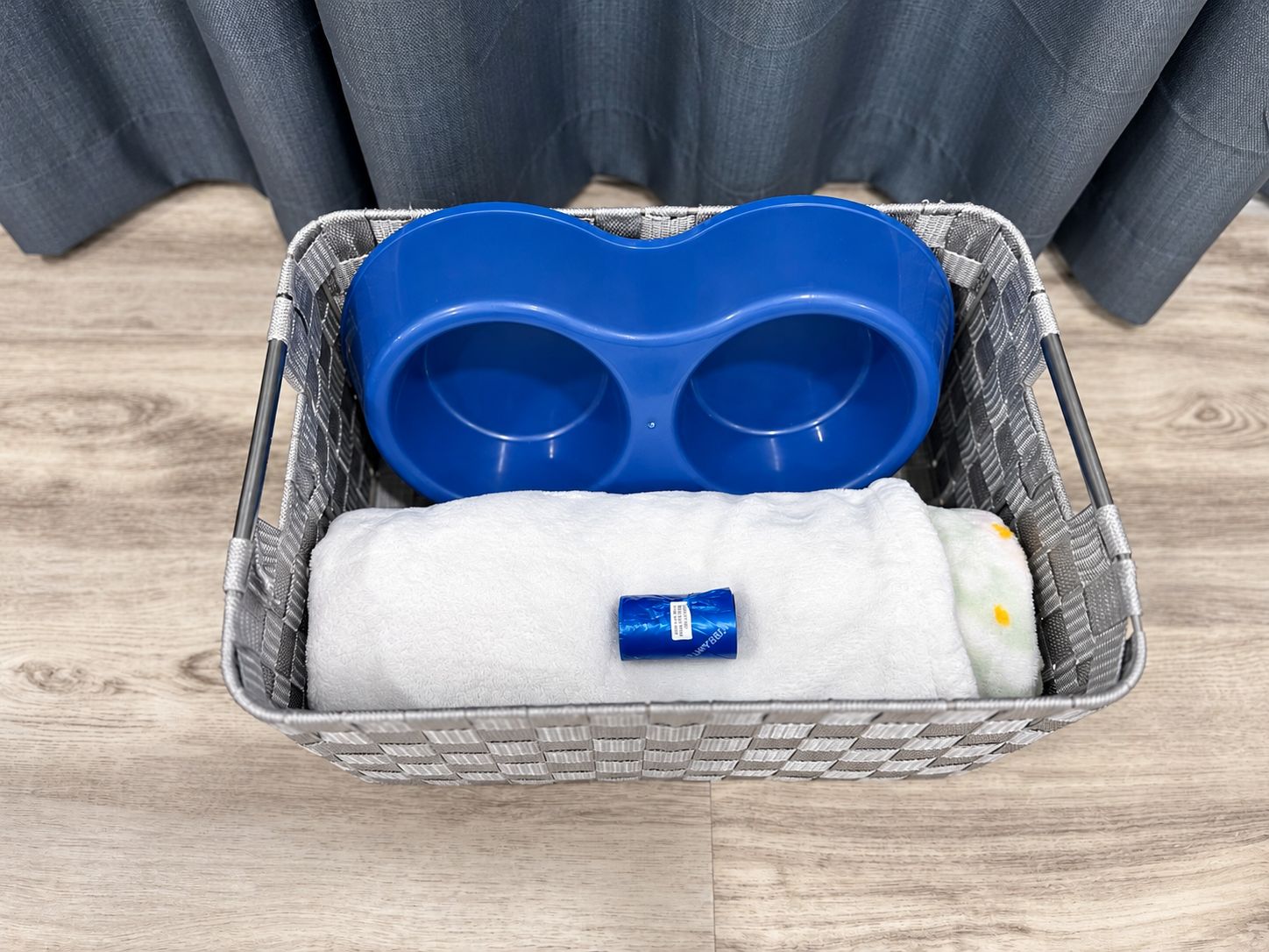 A basket containing a blue object, a white towel, and a small item.