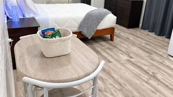 A hotel room with a bed, a television, a desk with a chair, and a small table with a basket.