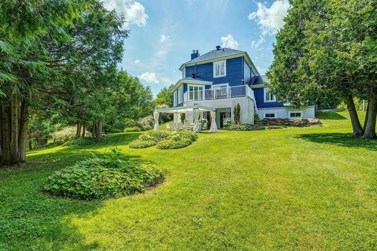 A two-story house with a covered porch, surrounded by a well-maintained lawn and trees.