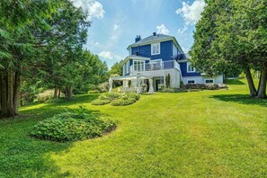 A two-story house with a covered porch, surrounded by a well-maintained lawn and trees. - Sutton Mountain View (Sutton)