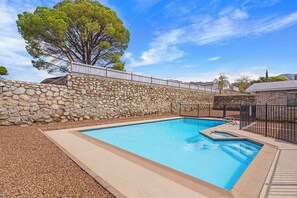 A swimming pool with a stone wall and a metal fence. - El Paso Desert Oasis (El Paso)