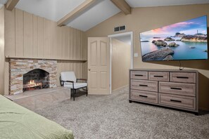 A room with a stone fireplace, a television mounted on the wall, and a wooden dresser. - El Paso Desert Oasis (El Paso)