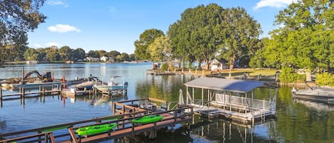 A lakeside dock with boats, a covered seating area, and a view of the lake and surrounding trees.