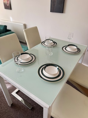 Una mesa de comedor dispuesta con platos, vasos y cubiertos, rodeada de sillas.