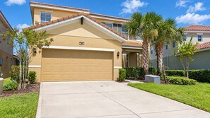 A residential building with a garage, a clear sky, and well-maintained landscaping. - Spacious 5BR Solterra Retreat with Private Pool (Davenport)