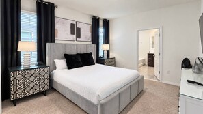 A bedroom with a large bed, two bedside tables, a dresser, and a door leading to another room. - Spacious 5BR Solterra Retreat with Private Pool (Davenport)
