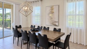 A dining area with a rectangular table, black chairs, a chandelier, and a large abstract painting on the wall. - Spacious 5BR Solterra Retreat with Private Pool (Davenport)