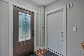 A hallway with a wooden door with a frosted glass window, a white door, and a tiled floor. - ADA Access - NIH & Walter Reed in Walking Distance (Bethesda)