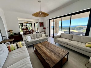 Ein geräumiger Wohnbereich mit großem Fenster und Panoramablick, ein Essbereich mit Tisch und Stühlen sowie eine gemütliche Sitzecke mit Sofas und Couchtisch.