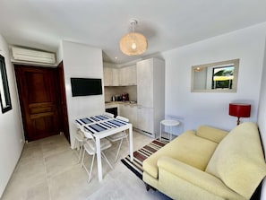 A compact living space with a dining area, kitchenette, and a sofa. - VILLA NEAR THE BEACH WITH SWIMMING POOL AND LOVELY SEA VIEWS TO RENT FOR 10 PEOPLE (STE MAXIME)