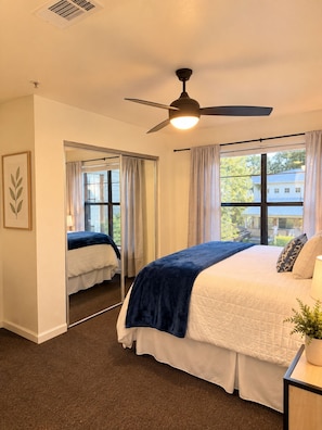 A bedroom with a bed, a ceiling fan, a window with curtains, and a view of the outside. - The End Zone | Free Shuttle! (Athens)