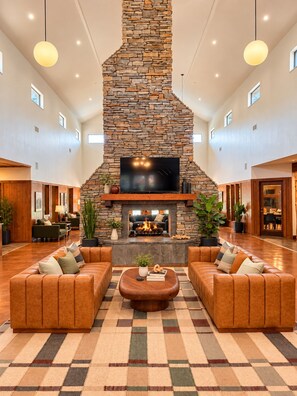 A spacious lobby with a stone fireplace, leather sofas, and a flat-screen TV. - The End Zone | Free Shuttle! (Athens)
