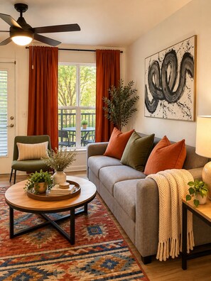 A living room with a sofa, armchairs, a coffee table, and a ceiling fan. - Red Zone Suite w/ Free Shuttle! (Athens)