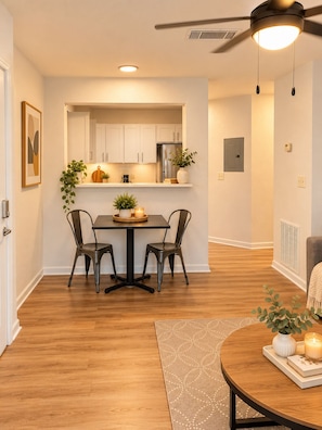 A modern kitchen with white cabinets, a stainless steel refrigerator, and a dining area with two chairs and a table. - The Athens Playbook w/ Pool & Shuttle! (Athens)