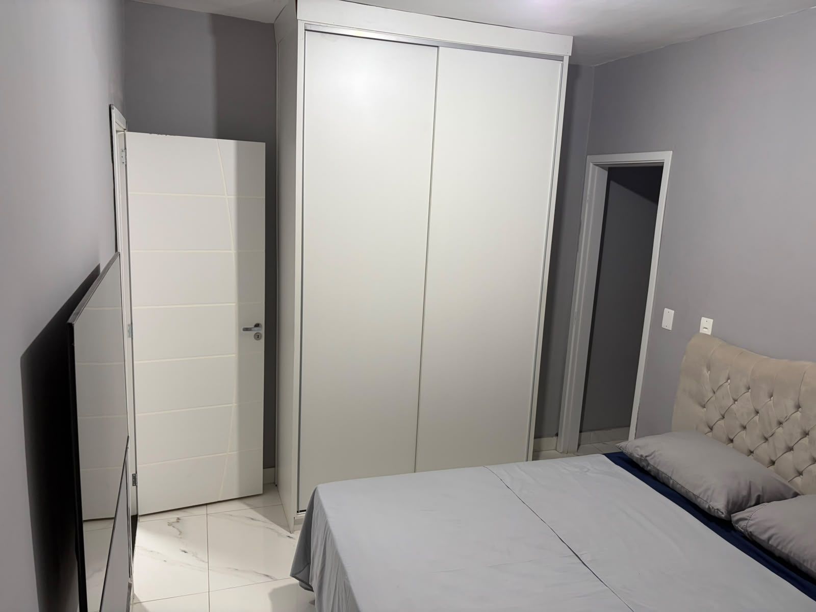 A bedroom with a bed, a wardrobe, and a door.