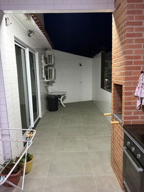 Un pequeño patio amurallado con suelo de baldosas, un horno de ladrillo y una mesa pequeña con una silla.